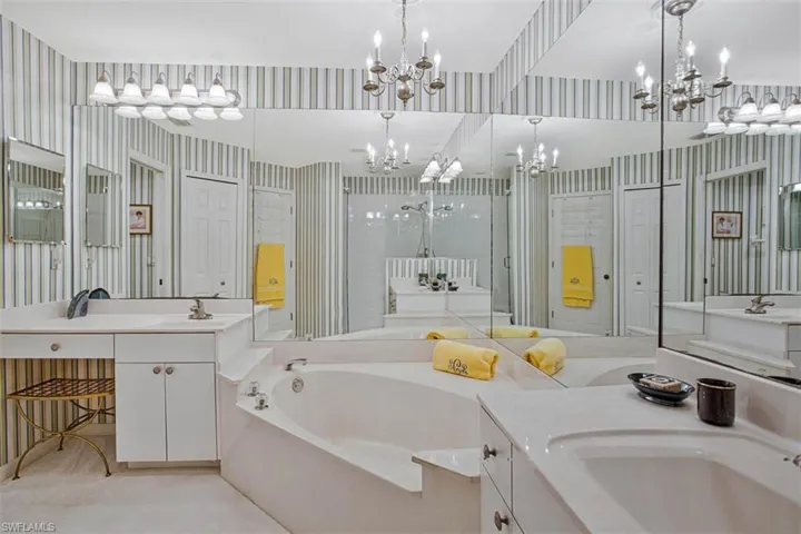 Bathroom featuring wallpapered walls, a bath, two vanities, and a shower stall