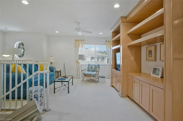 Living area featuring light colored carpet, an upstairs landing, ceiling fan, and recessed lighting
