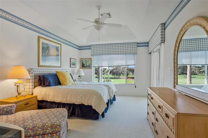 Carpeted bedroom featuring ceiling fan and a tray ceiling