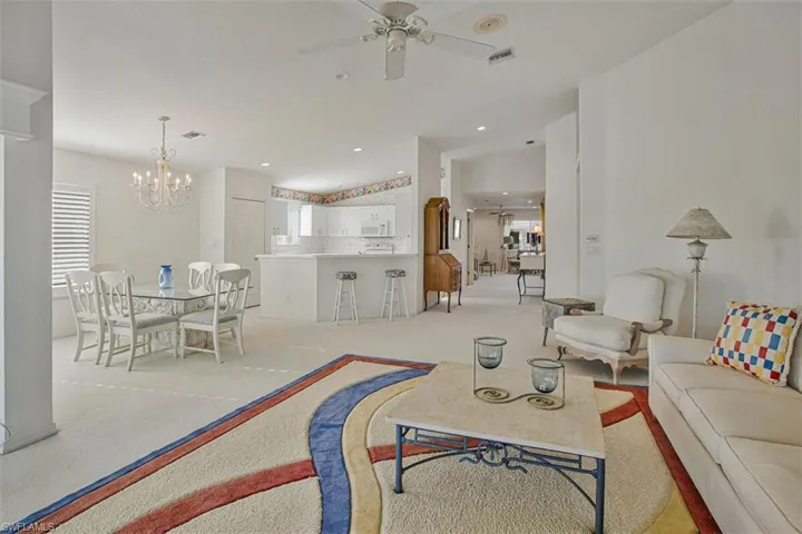 Carpeted living area featuring a ceiling fan, a chandelier, and recessed lighting