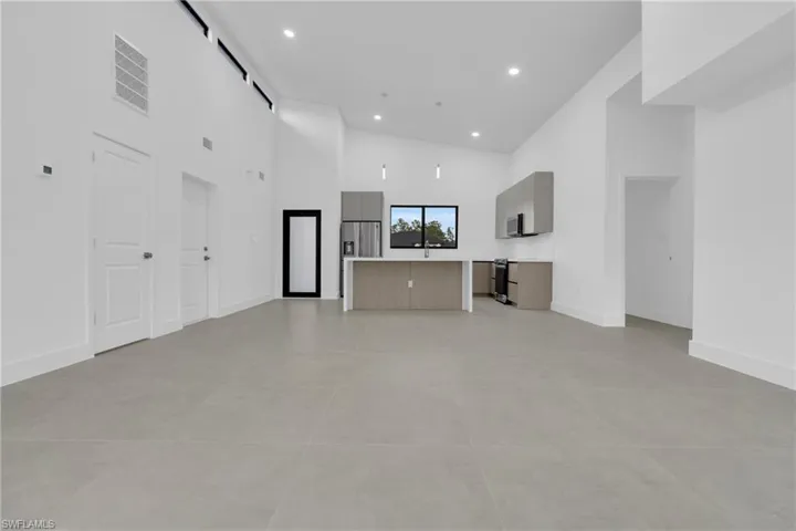 Unfurnished living room featuring a high ceiling and recessed lighting