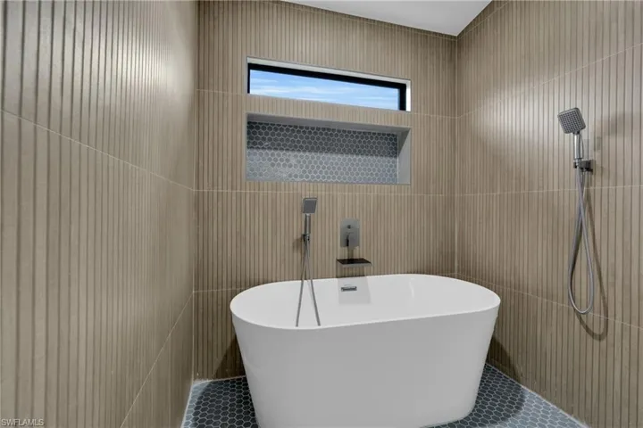 Full bath with a freestanding bath, tile walls, and tile patterned flooring