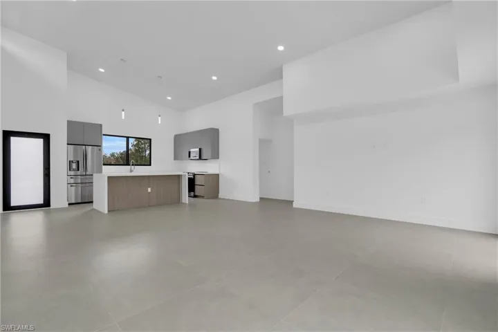 Unfurnished living room with high vaulted ceiling and recessed lighting