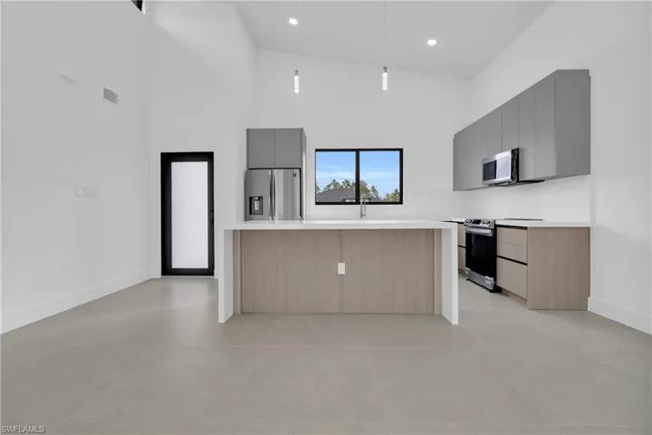 Kitchen featuring a kitchen island, modern cabinets, high vaulted ceiling, stainless steel appliances, and gray cabinetry
