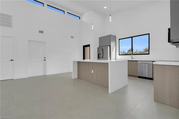 Kitchen with a center island, modern cabinets, decorative light fixtures, stainless steel appliances, and light brown cabinets
