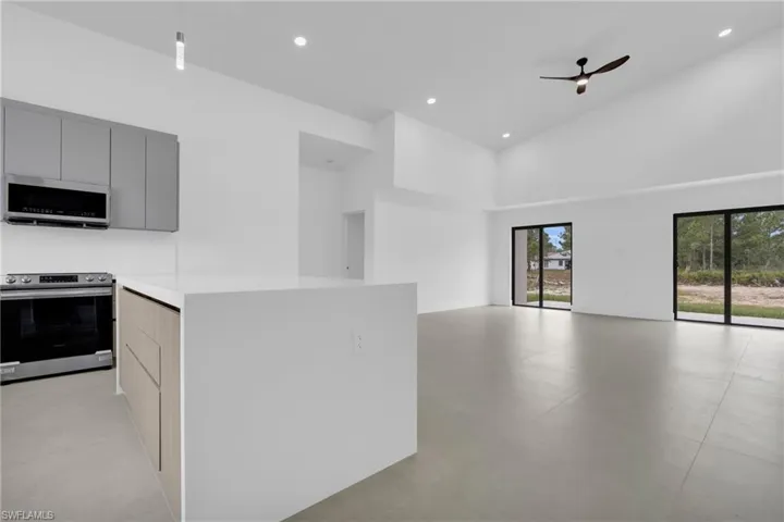Kitchen featuring appliances with stainless steel finishes, modern cabinets, a high ceiling, ceiling fan, and open floor plan