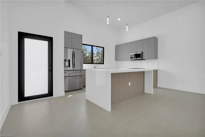 Kitchen featuring gray cabinetry, high vaulted ceiling, a kitchen island, stainless steel appliances, and modern cabinets