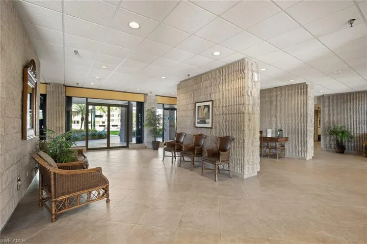 Spacious lobby featuring tile flooring, textured accent walls, recessed lighting, and glass entry doors
