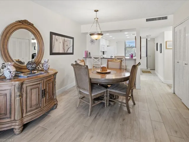 Open concept layout with wood-finish flooring, a built-in kitchen pass-through, and louvered bifold closet doors