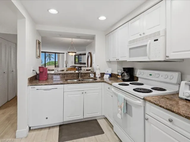 Kitchen featuring white cabinetry, brown granite-style countertops, white appliances, and recessed lighting