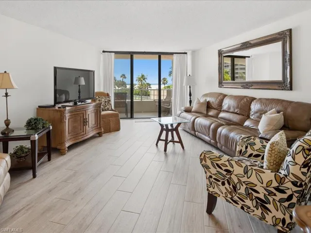 Sliding glass doors opening to a balcony, light wood-finish flooring, and a large ornate wall mirror