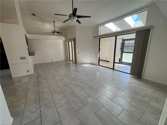 Empty room featuring high vaulted ceiling, ceiling fan, and light tile patterned flooring