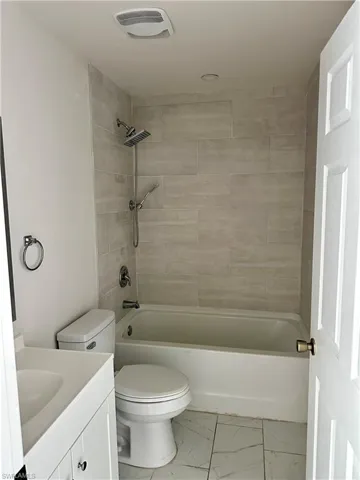 Bathroom featuring vanity, light marble finish floors, and shower / tub combination