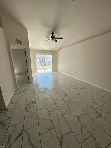 Spare room featuring light marble finish flooring, ceiling fan, and vaulted ceiling