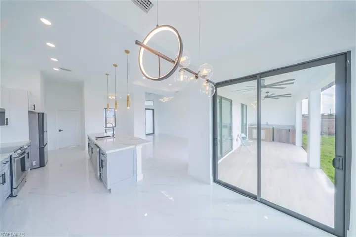 Kitchen featuring electric range, a kitchen island with sink, freestanding refrigerator, and open floor plan