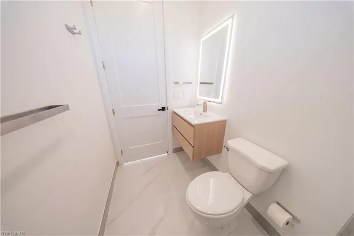 Half bath featuring vanity and light marble finish floors