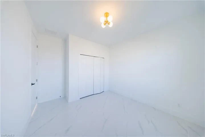 Unfurnished bedroom featuring a closet and light marble finish flooring