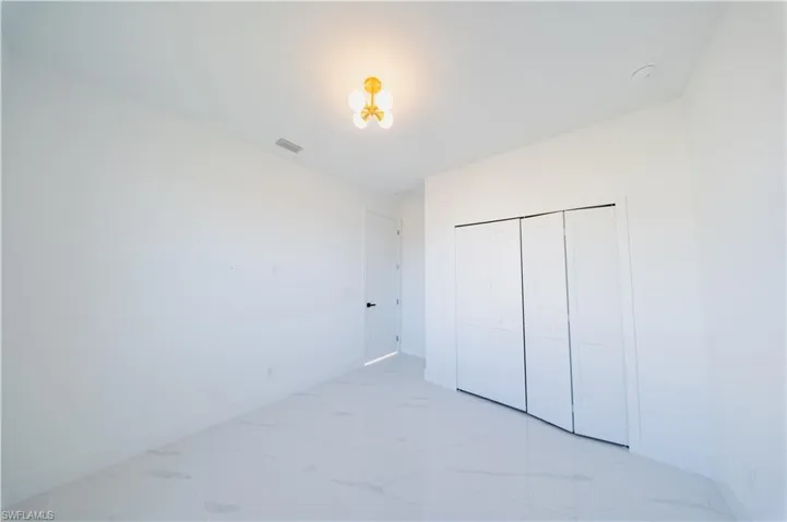 Unfurnished bedroom featuring a closet and light marble finish floors