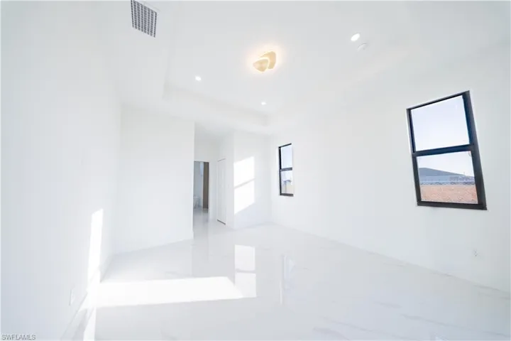 Unfurnished room featuring recessed lighting, light marble finish flooring, and a tray ceiling