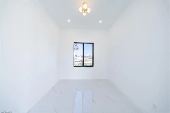 Empty room with light marble finish floors and recessed lighting