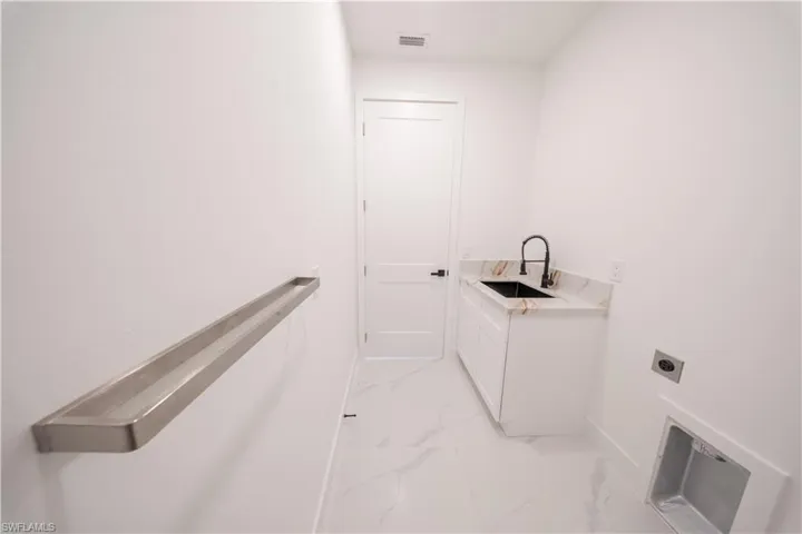 Laundry room featuring light marble finish flooring, hookup for an electric dryer, and cabinet space