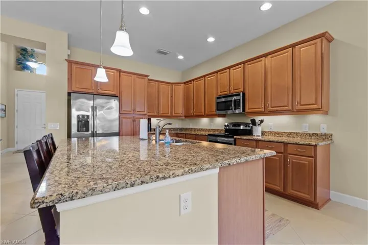 Spacious kitchen featuring a large island with stone countertops, stainless steel appliances, abundant cabinetry, and recessed lighting