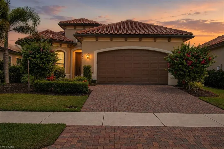 Mediterranean-inspired residence featuring a terracotta tile roof, stucco exterior, and a brick paver driveway