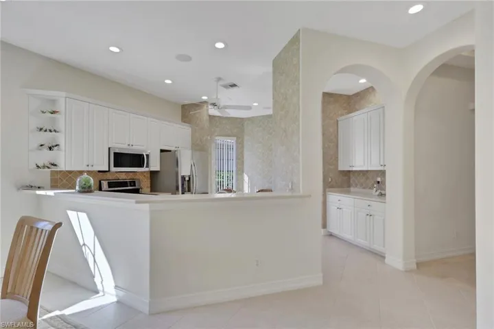 Kitchen featuring white cabinets, backsplash, appliances with stainless steel finishes, light countertops, and recessed lighting