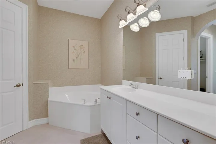 Full bathroom with a bath, vanity, and wallpapered walls