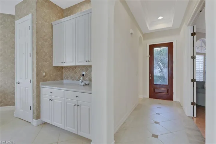 Entrance foyer with arched walkways, light tile patterned floors, crown molding, recessed lighting, and a raised ceiling