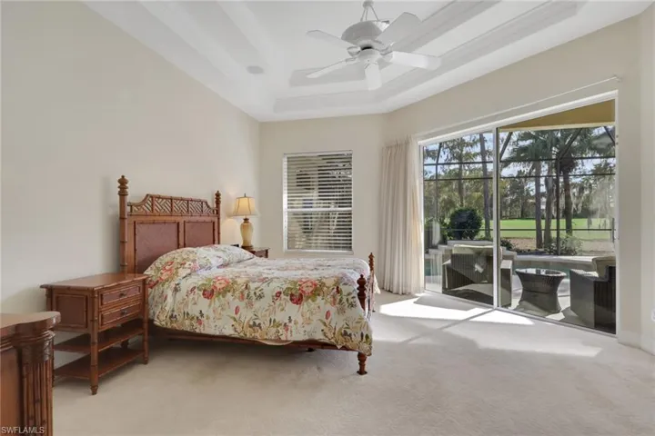 Bedroom featuring a raised ceiling, access to outside, light colored carpet, and a ceiling fan