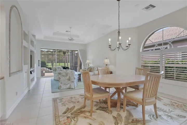 Dining space featuring light tile patterned floors, a tray ceiling, a ceiling fan, a sunroom, and a chandelier