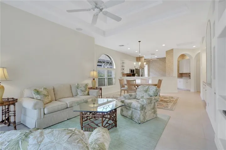 Living room with a tray ceiling, a ceiling fan, and a chandelier