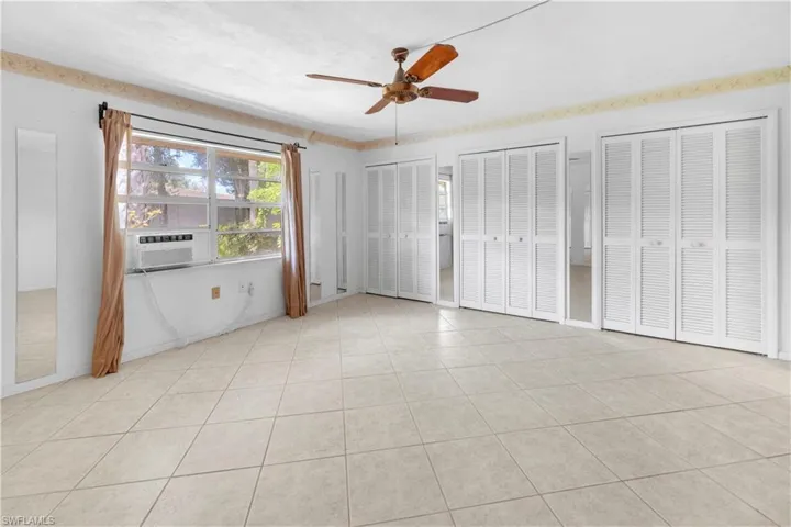 bedroom featuring multiple closets, light tile flooring, and ceiling fan
