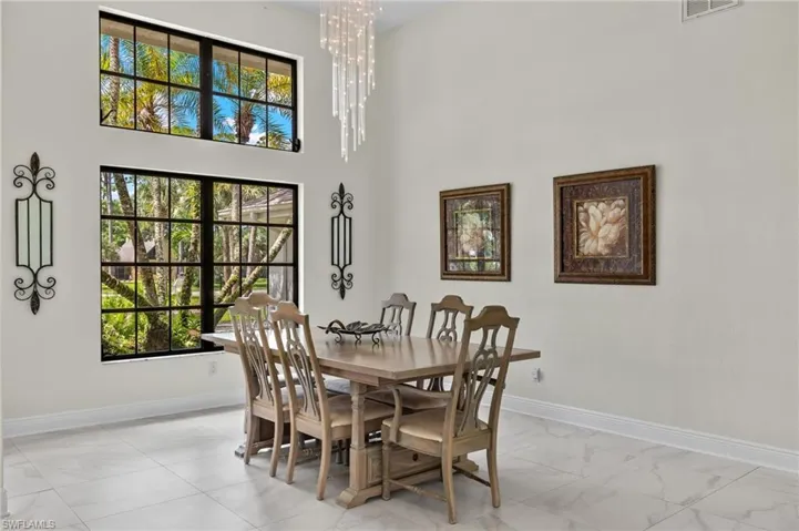 Dining room featuring a chandelier, marble finish floor, baseboards, and plenty of natural light