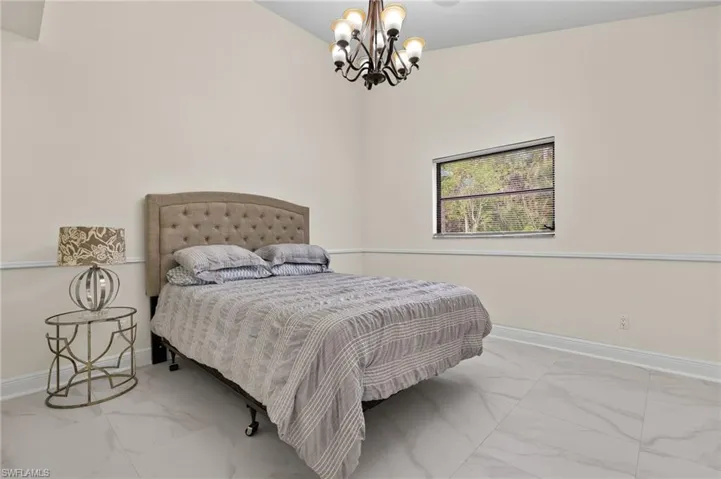 Bedroom featuring baseboards, marble finish floor, and a chandelier