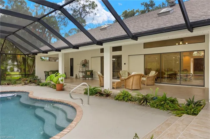 Rear view of house with a patio area, a lanai, stucco siding, and roof with shingles