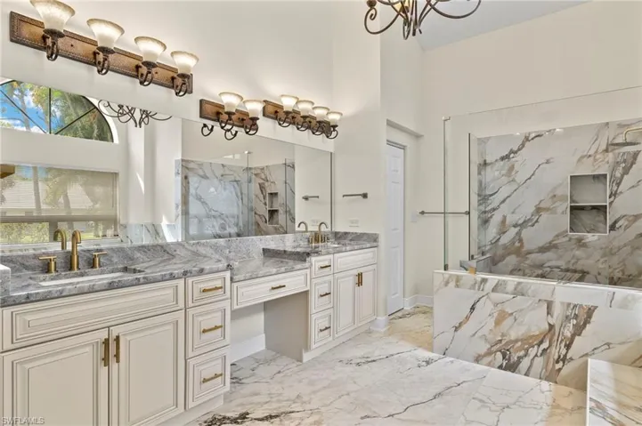 Full bath featuring double vanity, marble finish floor, a sink, and a marble finish shower