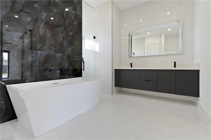 Bathroom with tile patterned flooring, vanity, and plus walk in shower