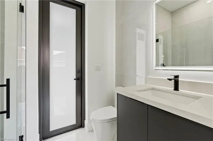 Bathroom featuring vanity, toilet, tile patterned flooring, and a shower with door