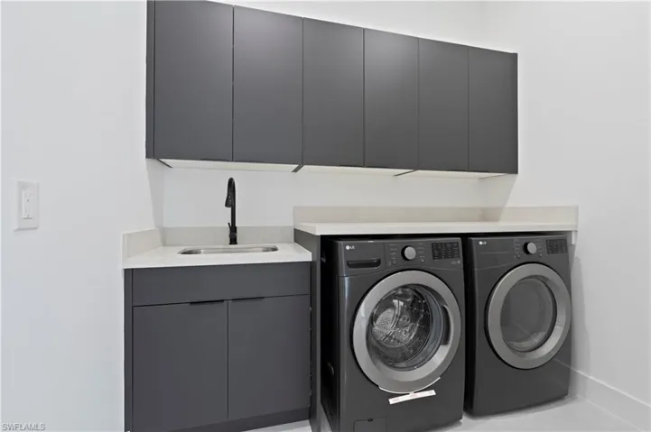 Washroom with cabinets, sink, and independent washer and dryer
