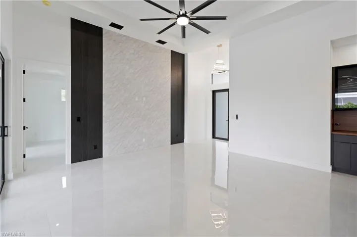 Spare room featuring tile walls, light tile patterned flooring, and ceiling fan