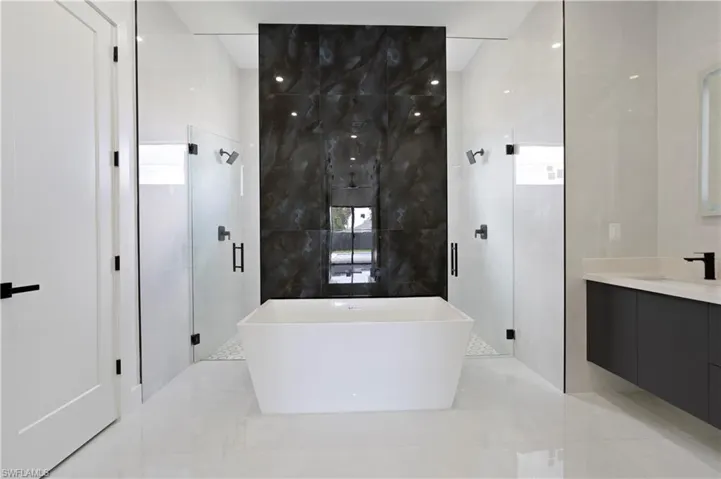Bathroom featuring vanity, independent shower and bath, and tile walls