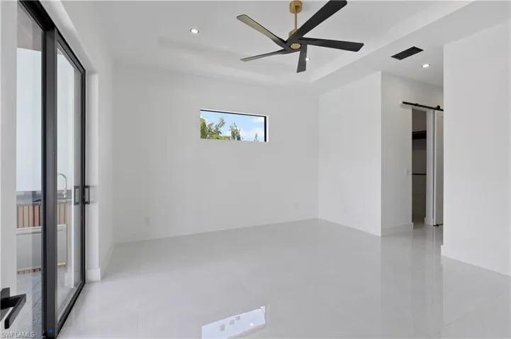 Unfurnished room featuring a barn door, ceiling fan, and a raised ceiling