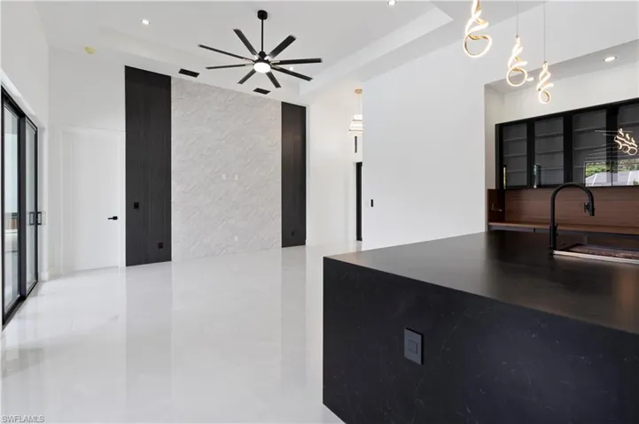 Kitchen featuring a raised ceiling, decorative light fixtures, sink, and ceiling fan