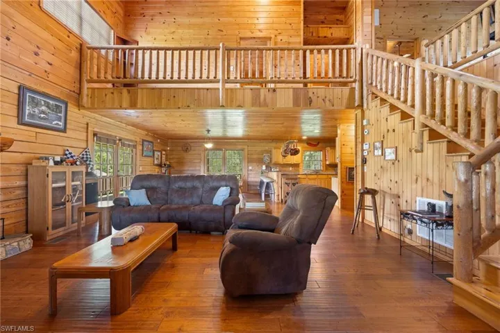 Living area with a high ceiling, wood walls, and hardwood / wood-style floors
