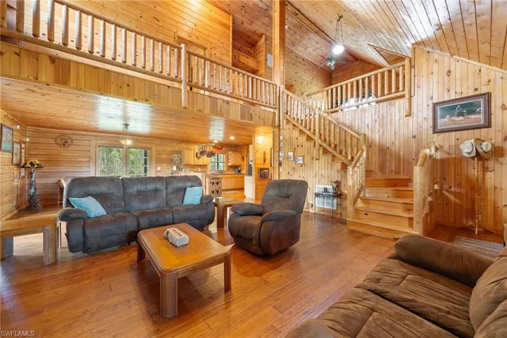 Living area featuring hardwood / wood-style flooring, wood walls, and a vaulted wood ceiling