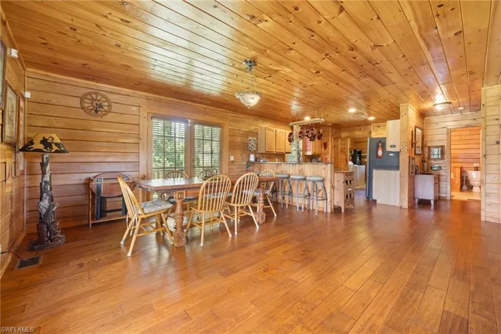 Dining room with wood walls, light wood-style floors, and wooden ceiling
