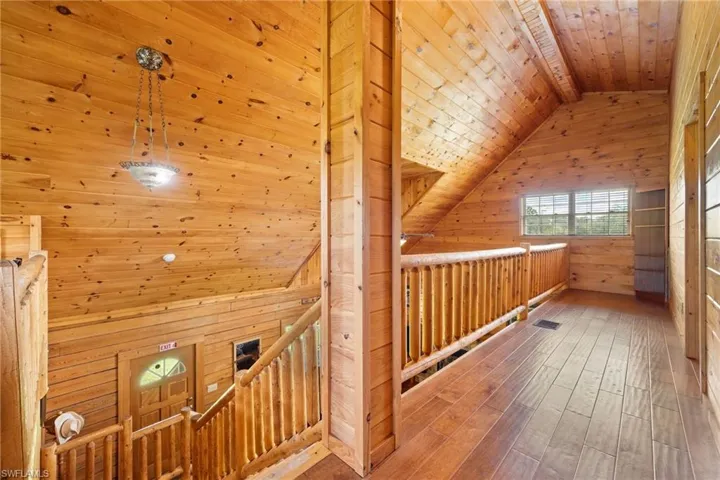 Hallway featuring wooden ceiling, wood walls, hardwood / wood-style flooring, and an upstairs landing