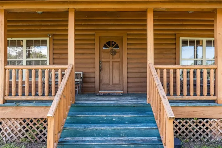 Doorway to property featuring log veneer siding and a porch